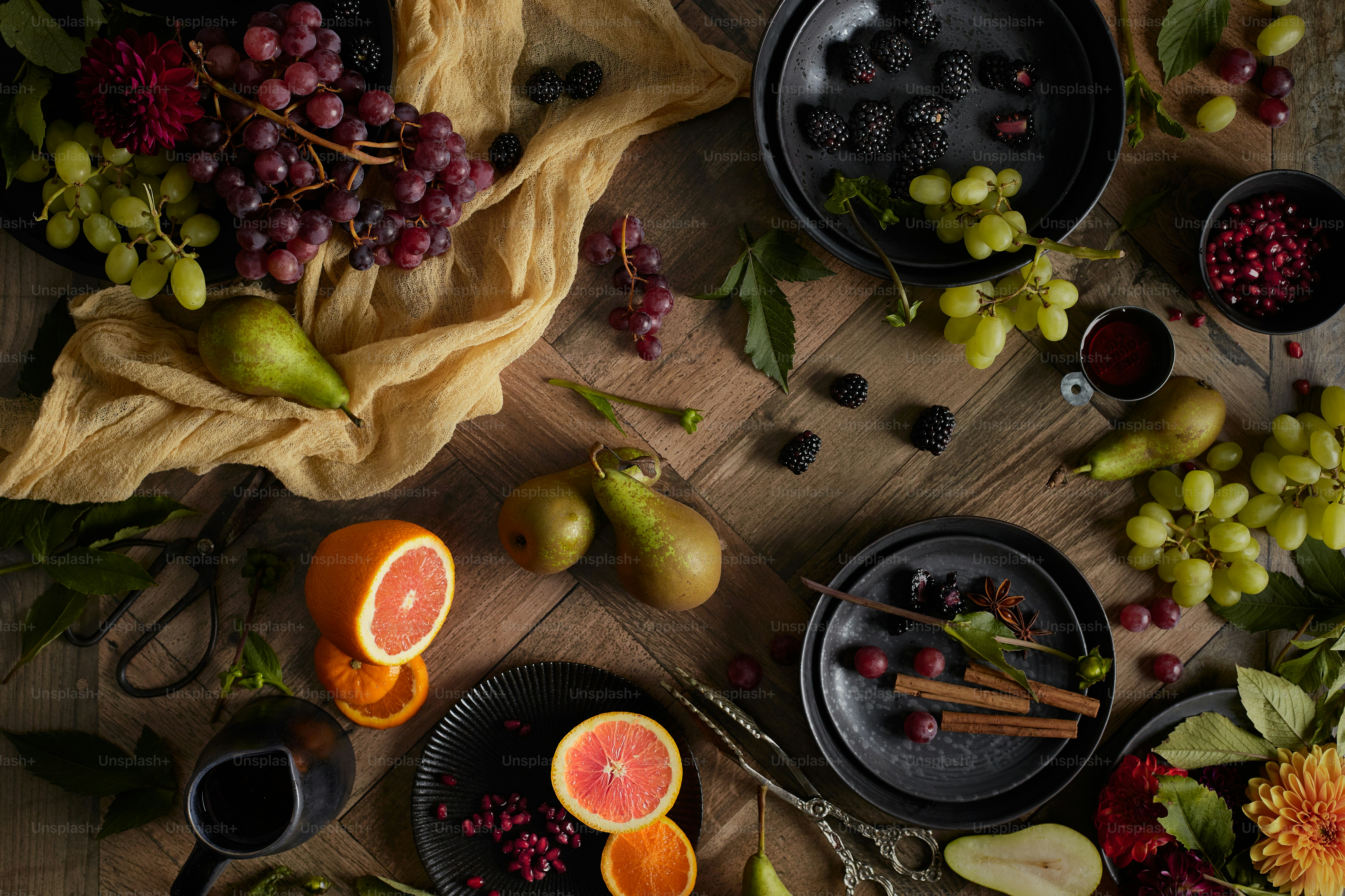 a wooden table topped with plates and bowls filled with fruit
