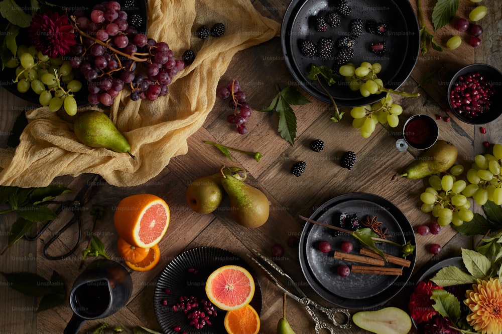 a wooden table topped with plates and bowls filled with fruit