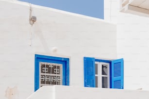 青いシャッターと時計のある白い建物