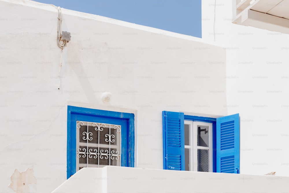 a white building with blue shutters and a clock