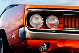 a close up of the front of an orange muscle car