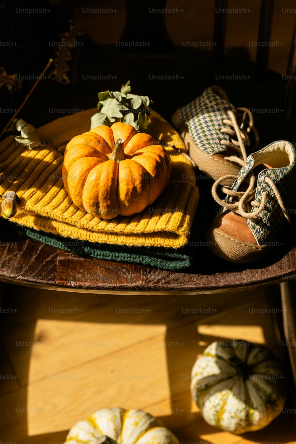 a wooden table topped with pumpkins and shoes