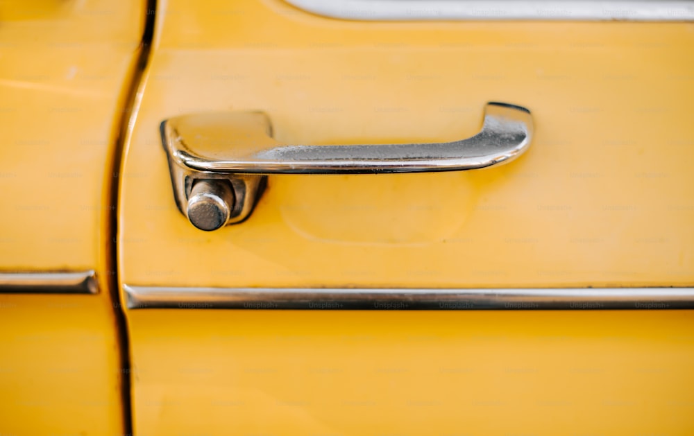 Un primer plano de la manija de una puerta en un coche amarillo