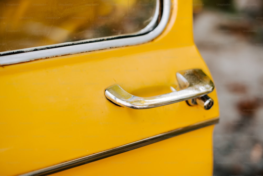 a close up of a door handle on a yellow car