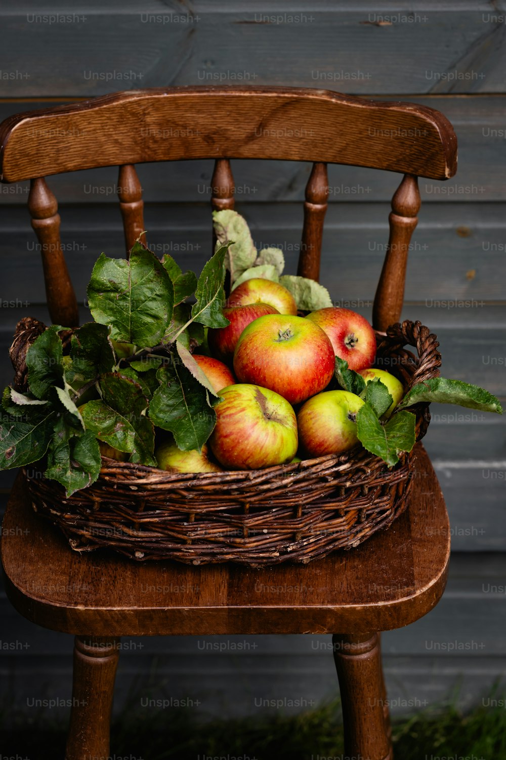 a basket full of apples sitting on a wooden chair