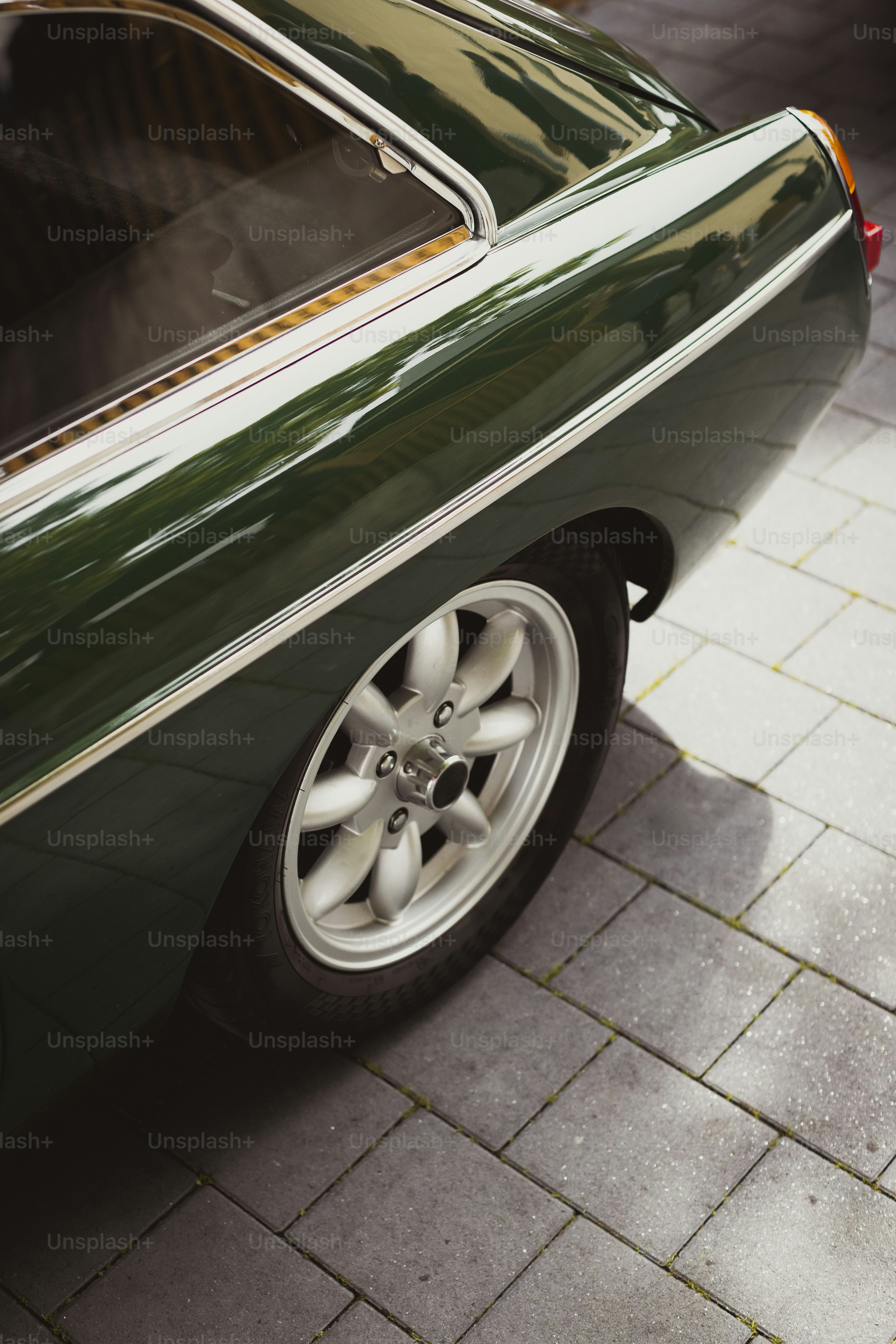 a green car parked on a brick sidewalk