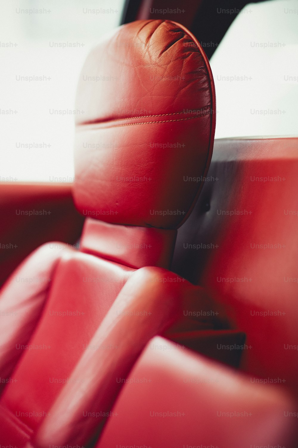 um assento de couro vermelho em um carro com volante