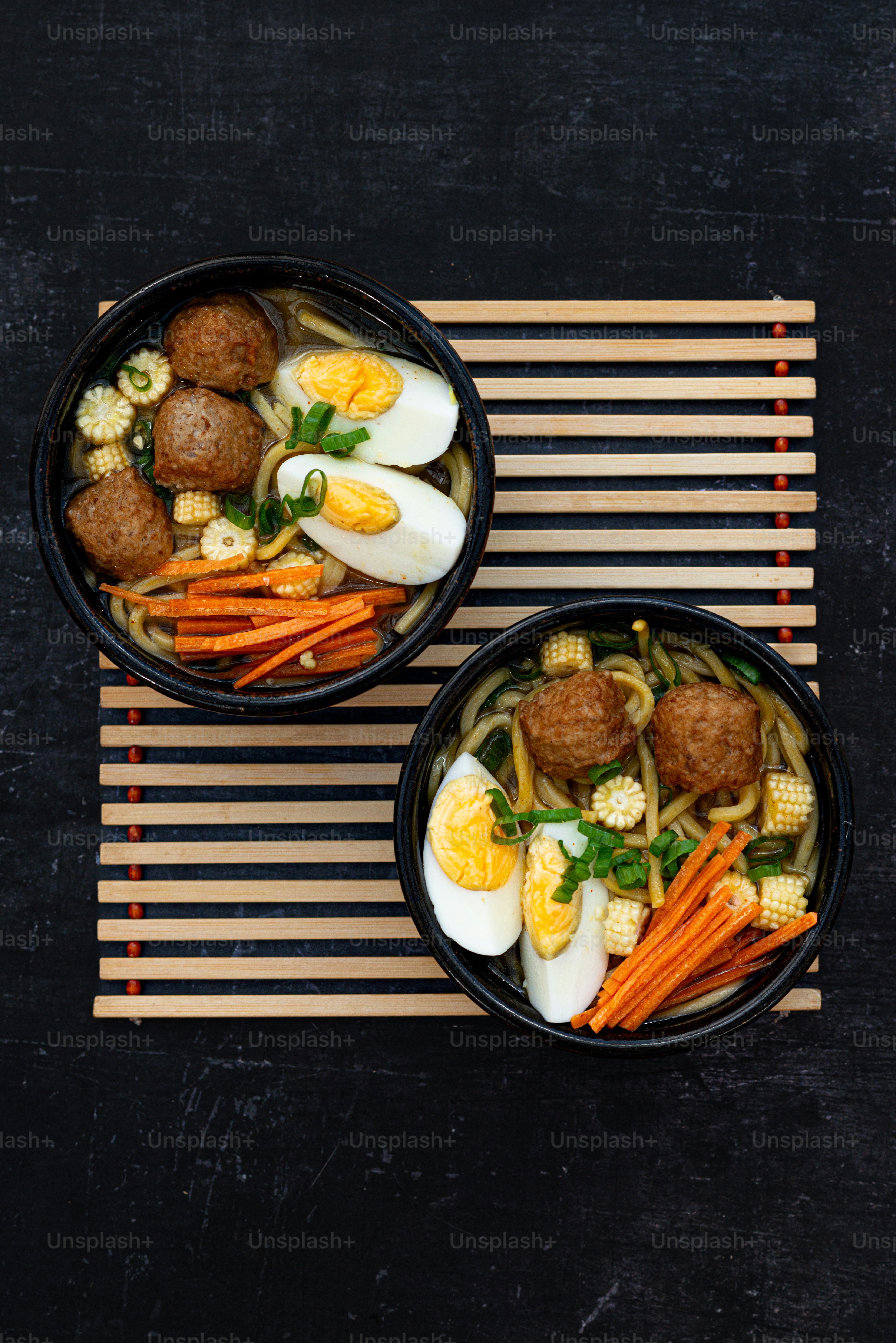 two black bowls filled with food on top of a table