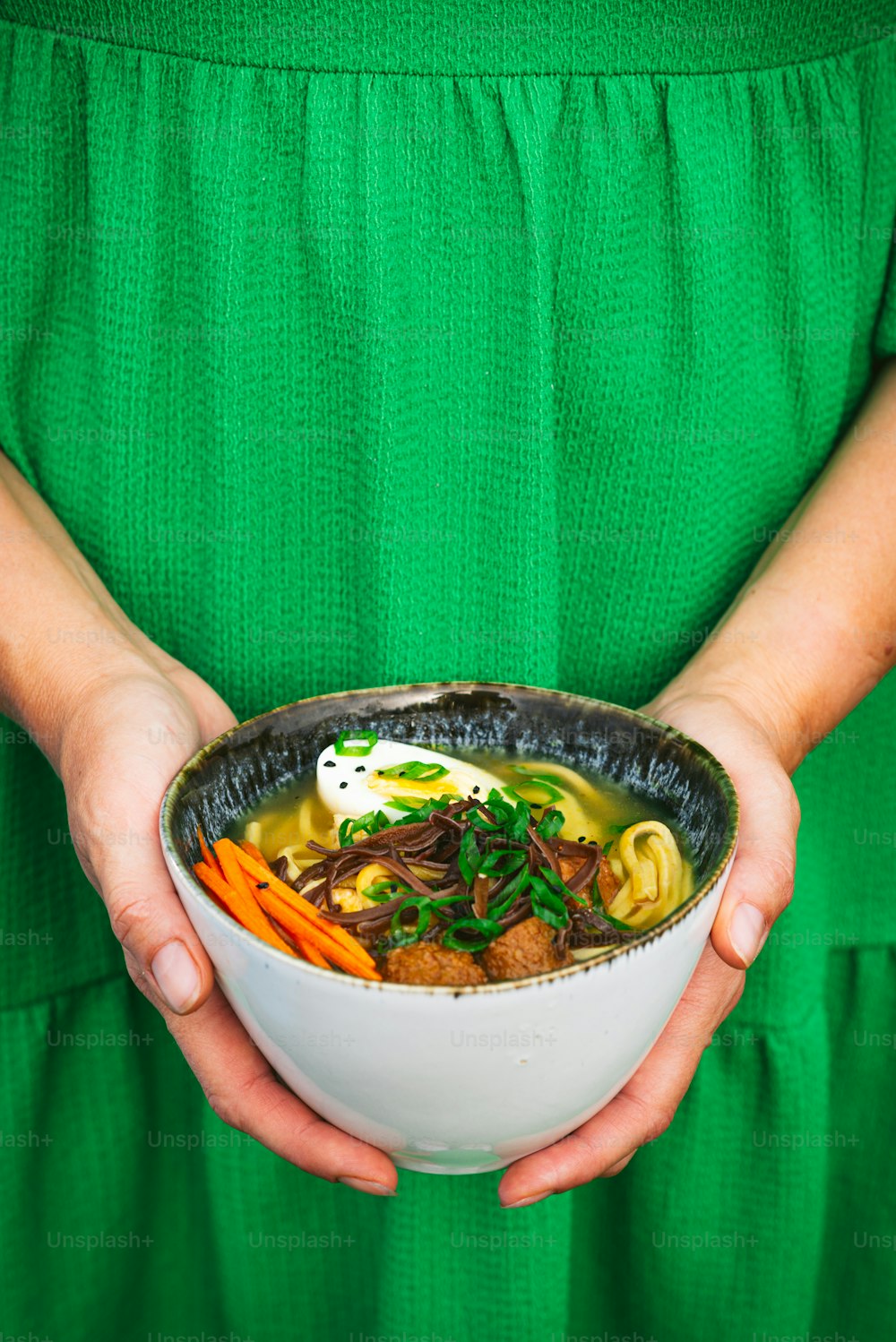 a woman in a green dress holding a bowl of food