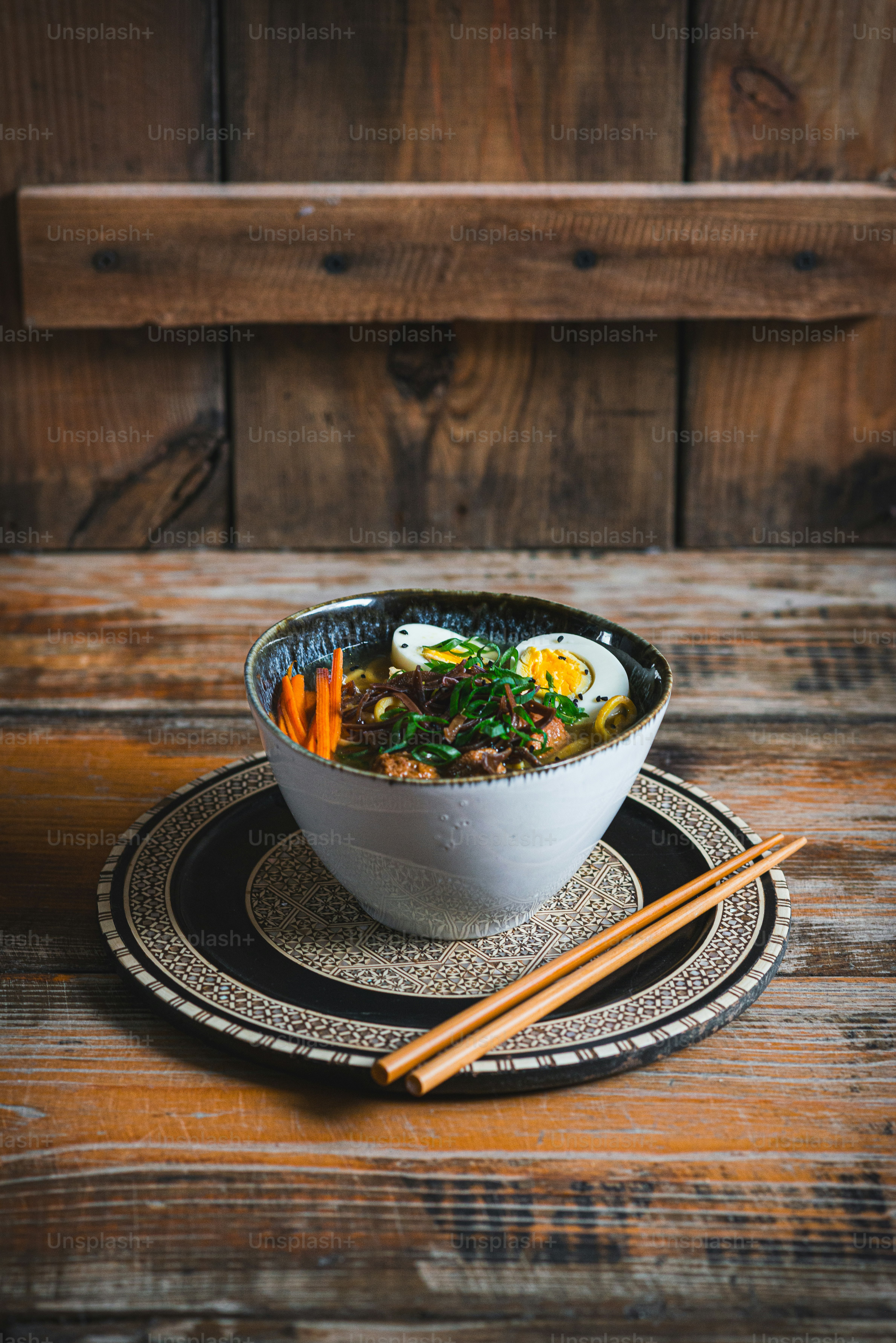 a bowl of soup on a plate with chopsticks