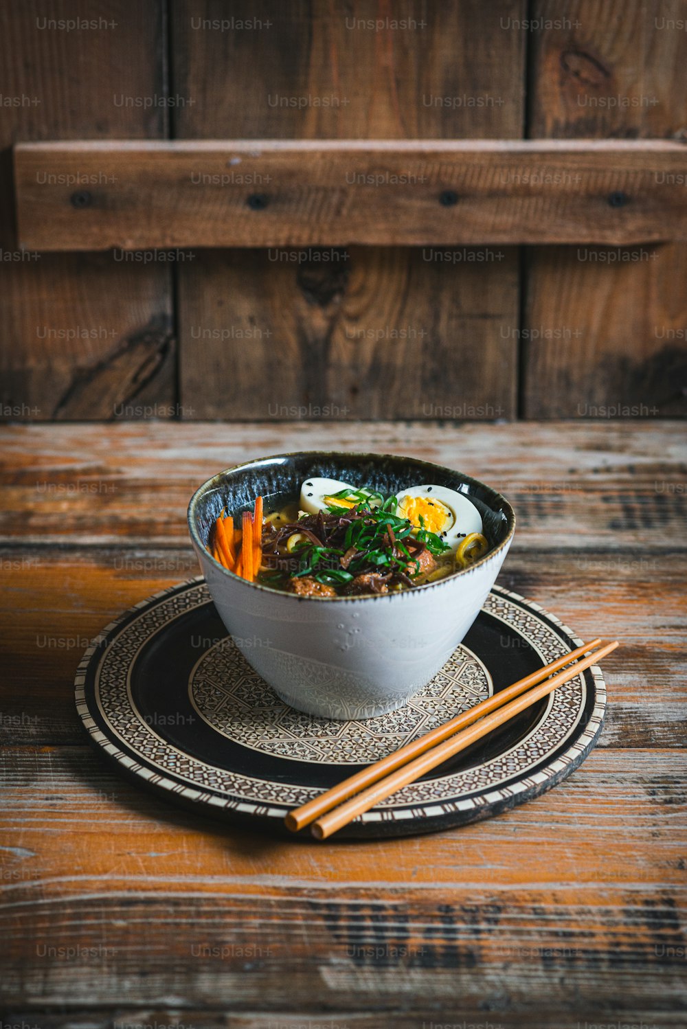 a bowl of soup on a plate with chopsticks