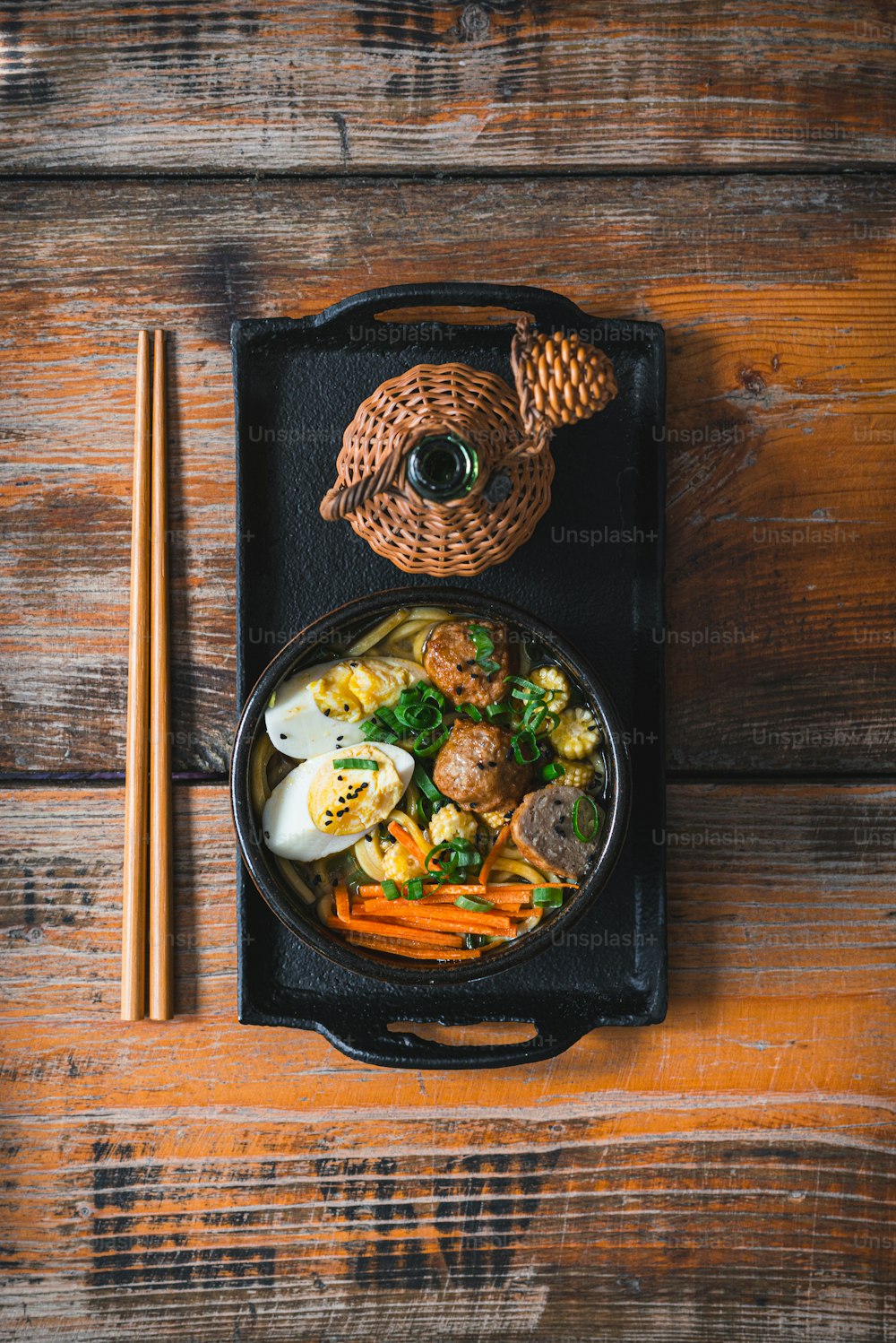 a bowl of food with chopsticks on a wooden table