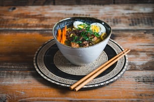 a bowl of soup on a plate with chopsticks