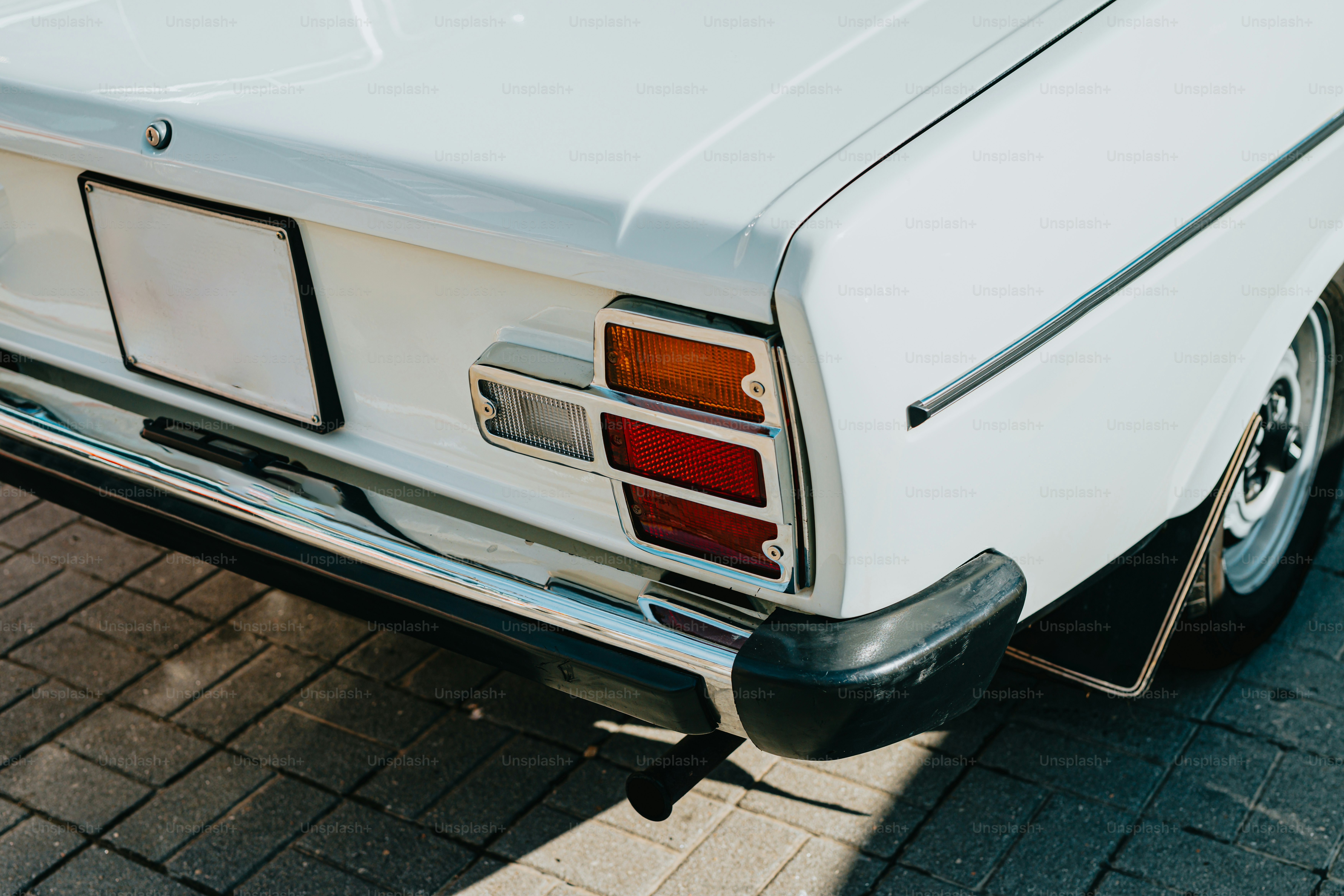 Une voiture blanche garée sur une route en briques