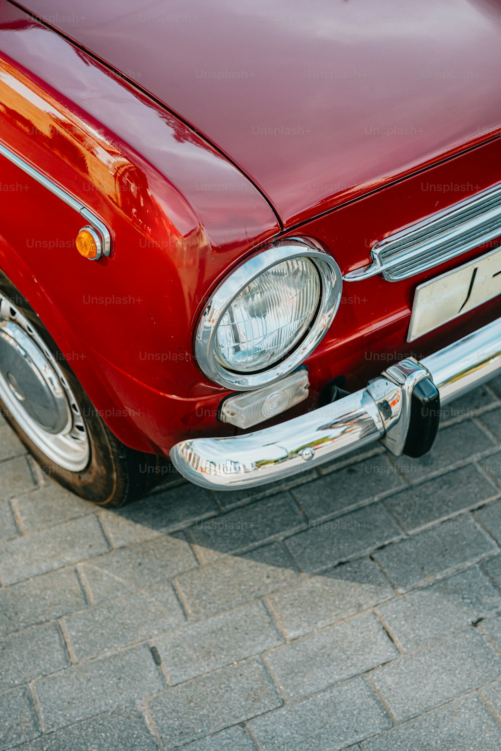 um carro vermelho estacionado em uma estrada de tijolos