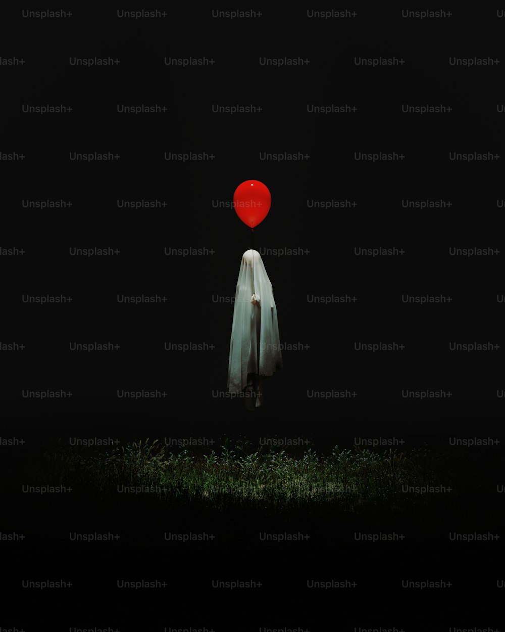 eine Person, die im Dunkeln mit einem roten Luftballon auf dem Kopf steht