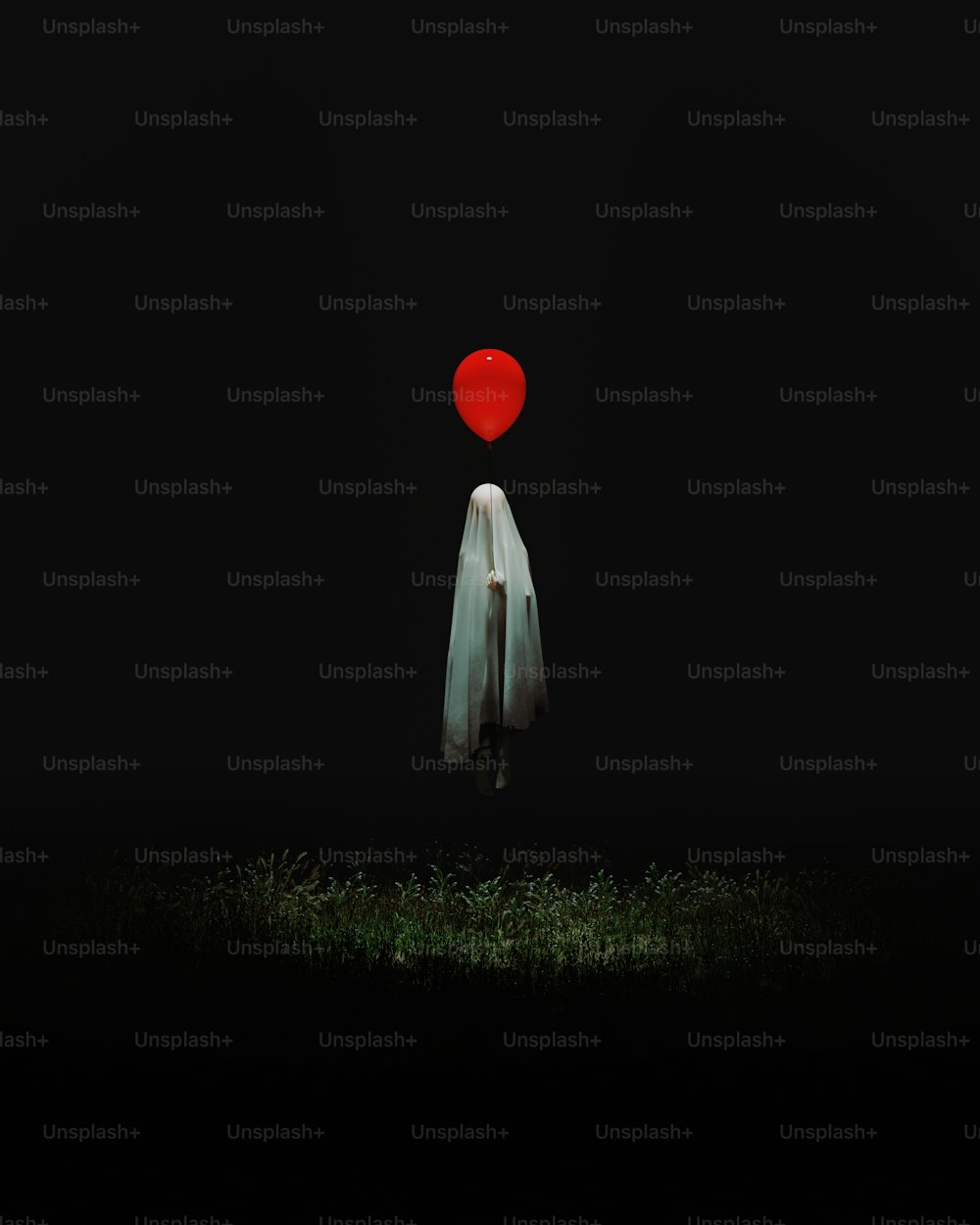 Una persona parada en la oscuridad con un globo rojo en la cabeza