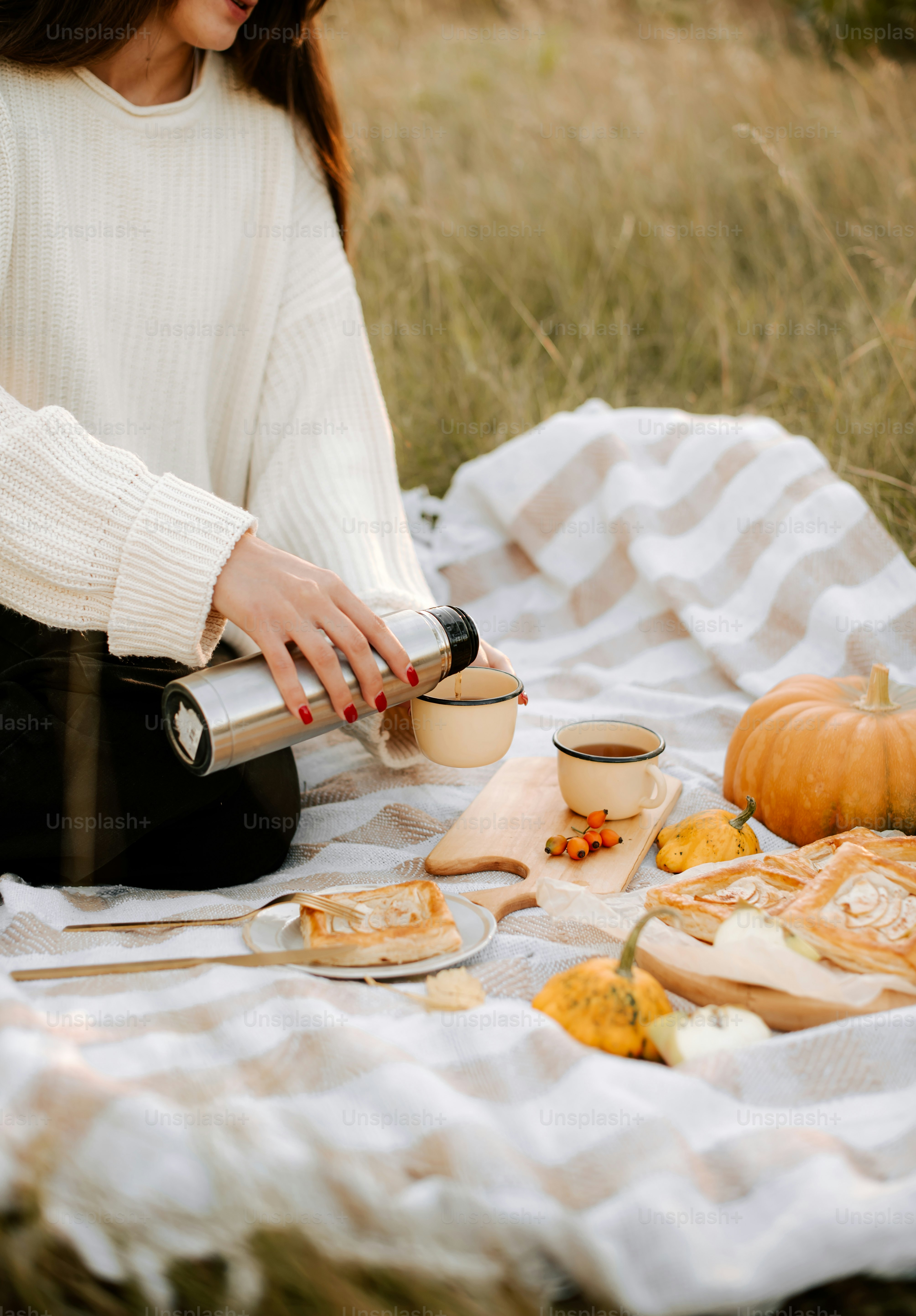 a woman sitting on a blanket with a cup of coffee