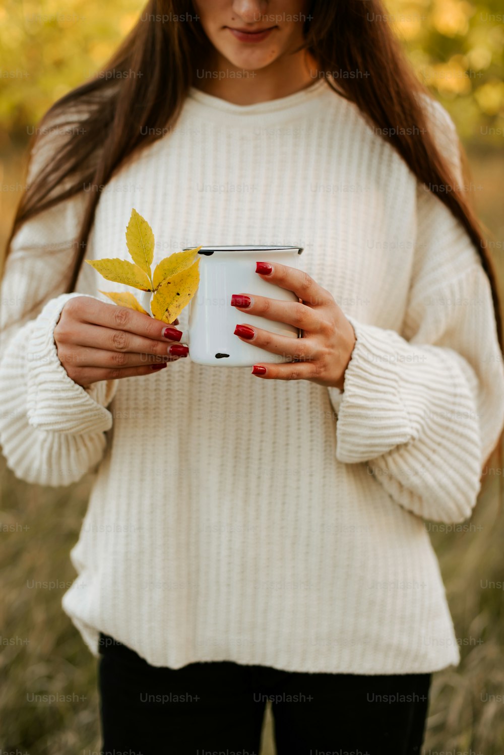 a woman holding a cup with a leaf on it