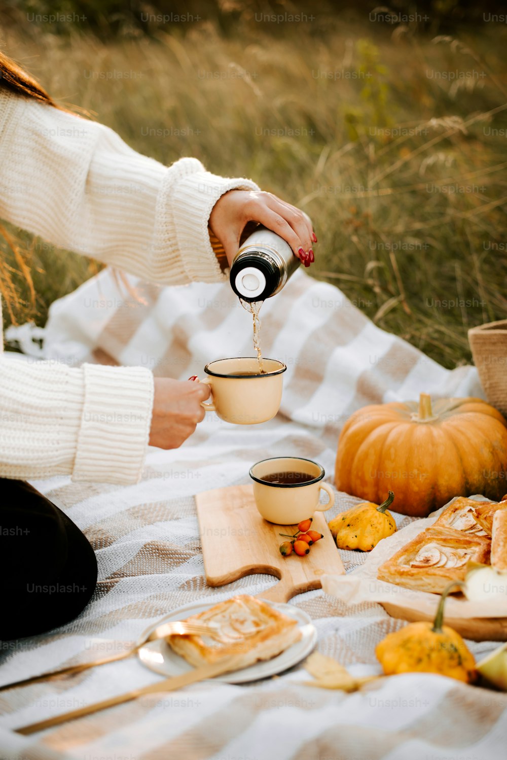 Eine Frau schenkt bei einem Picknick eine Tasse Kaffee ein