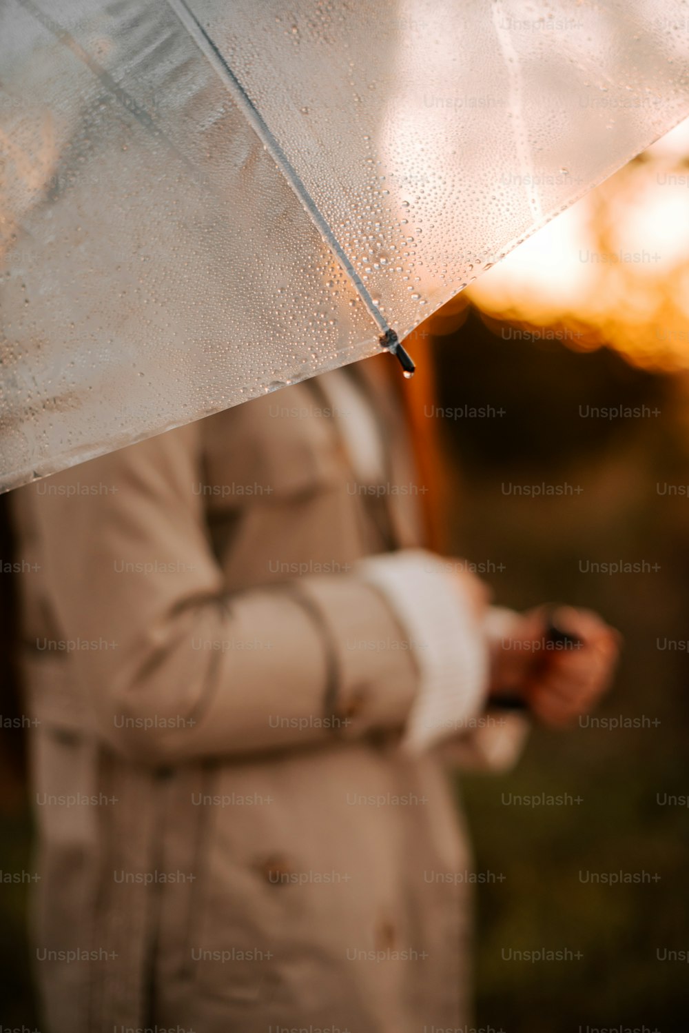 eine Frau in einem Trenchcoat, die einen Regenschirm hält