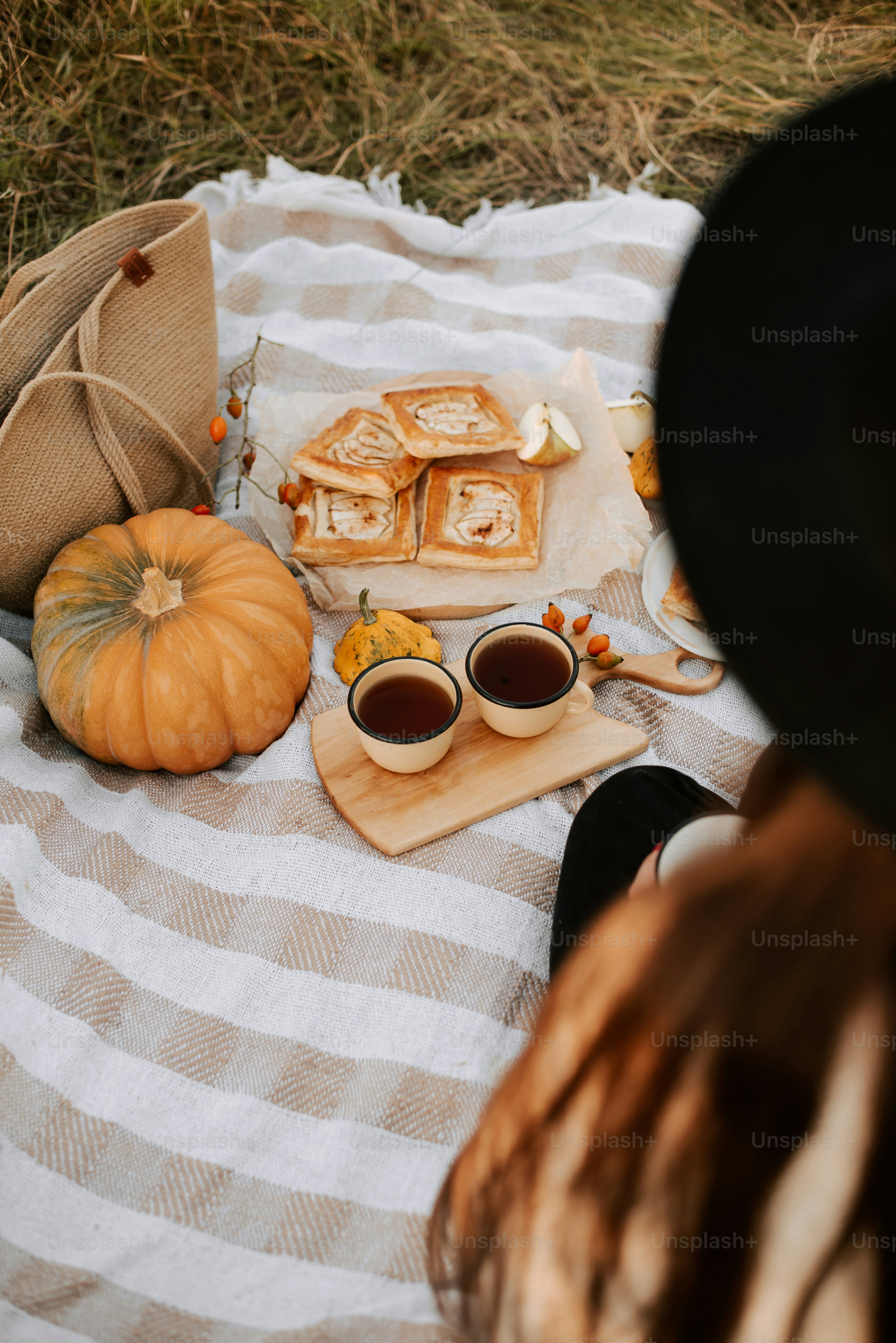 a woman sitting on a blanket with some food on it