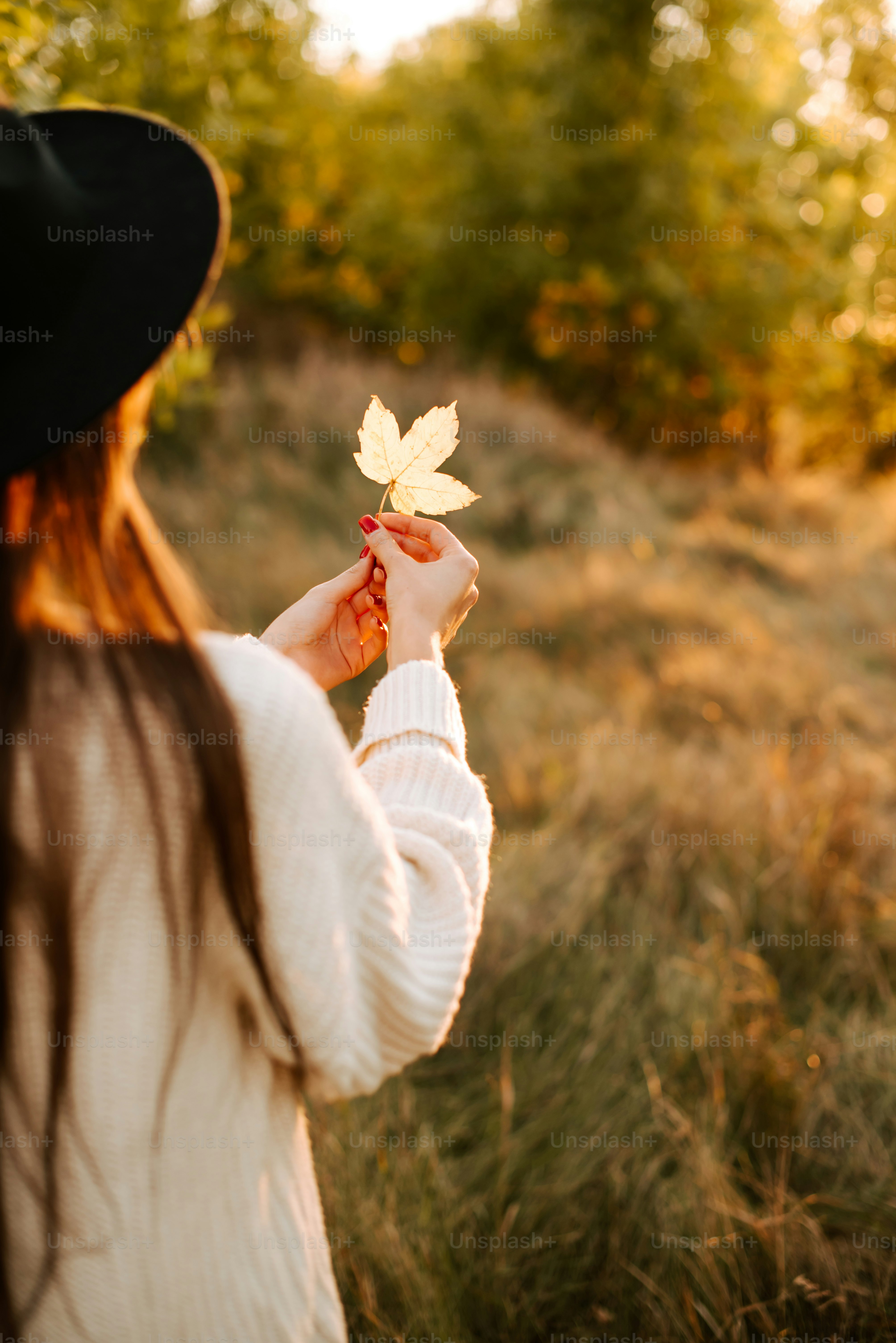 a woman in a black hat holding a leaf