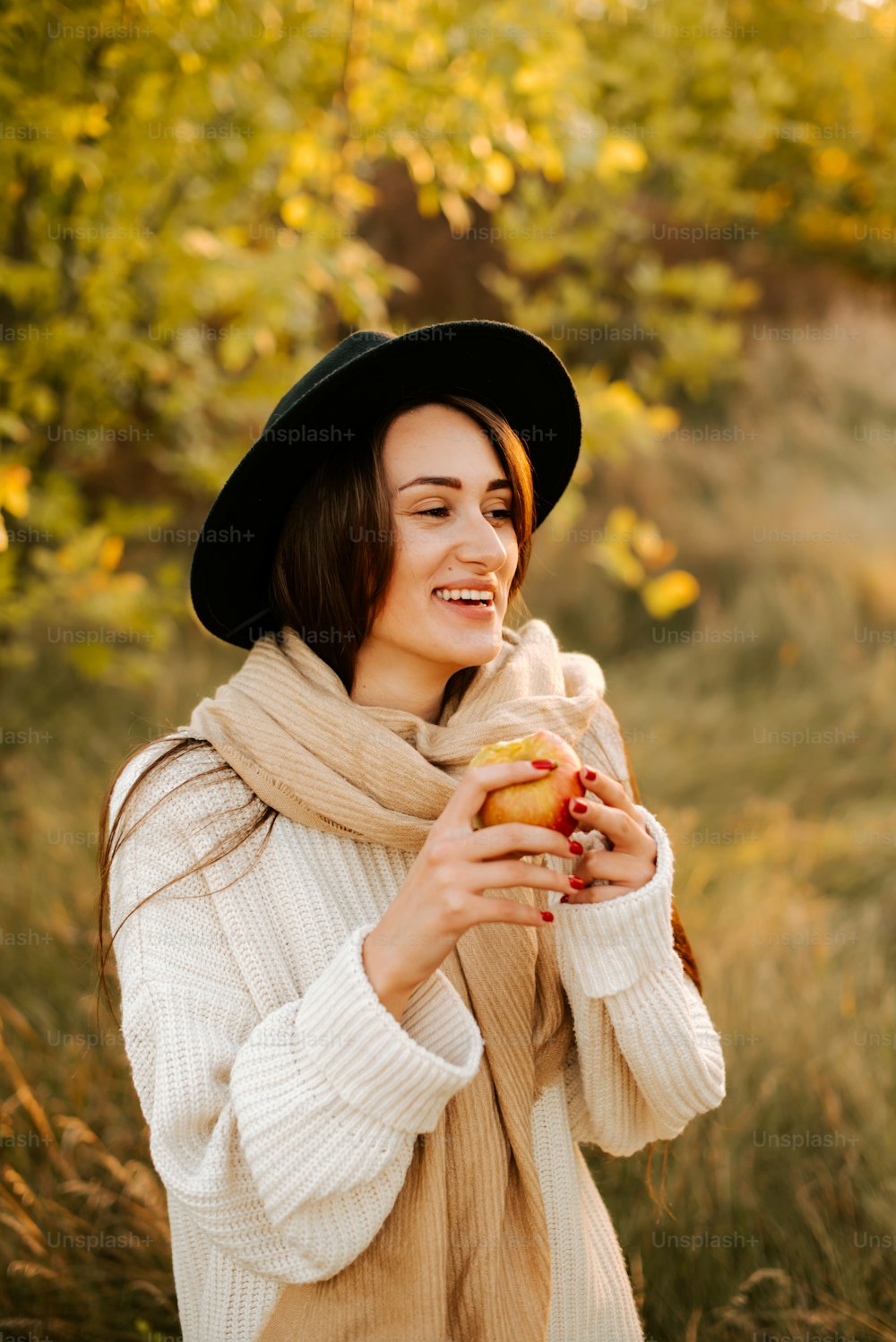 a woman wearing a hat and scarf holding a hot dog