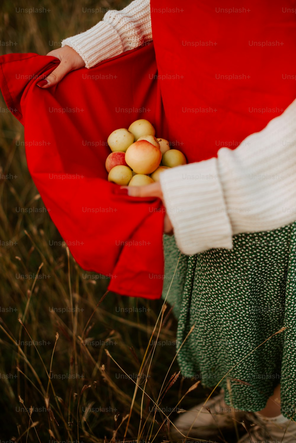 a woman holding a bunch of apples in her hands