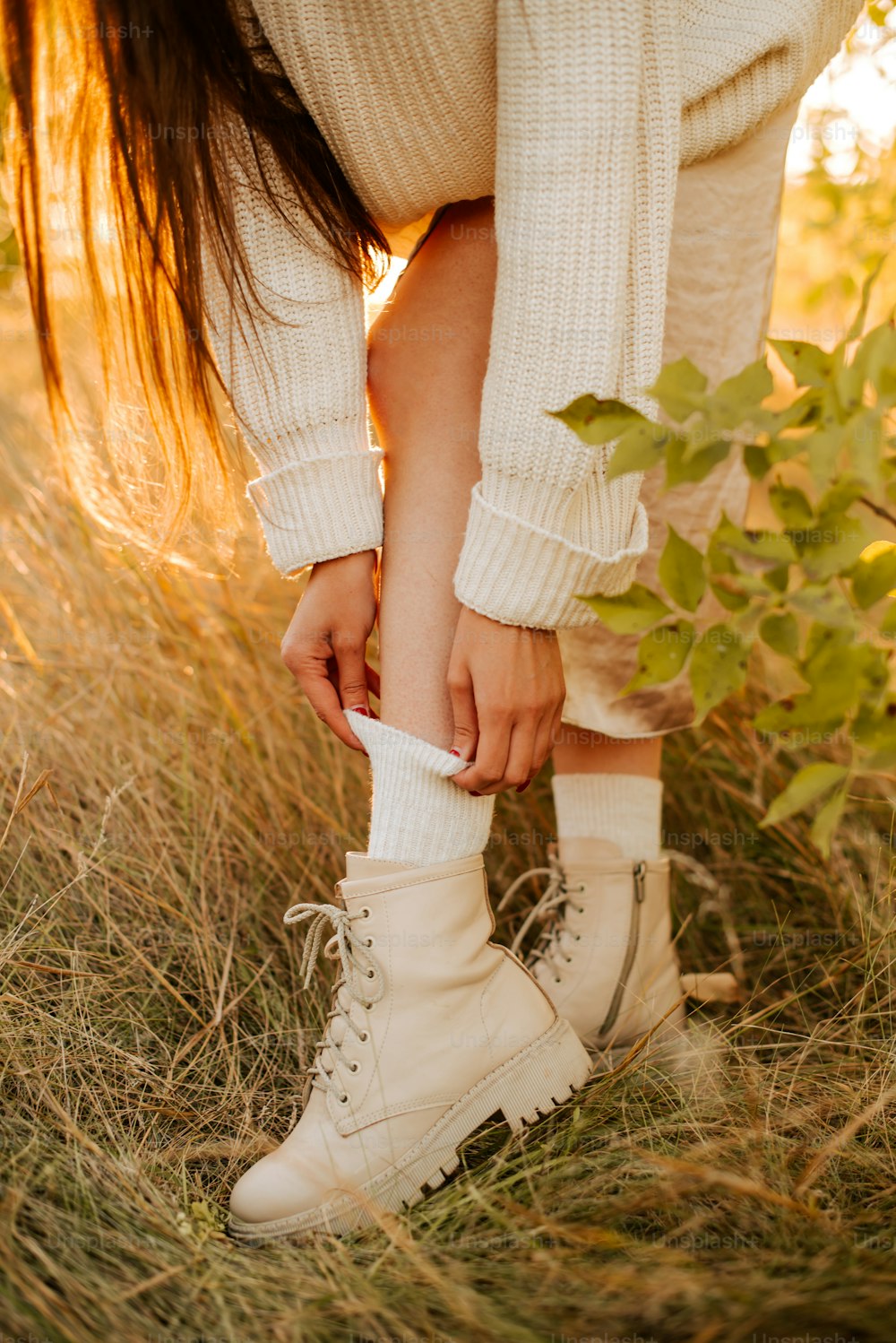 Una mujer con un suéter blanco y botas blancas