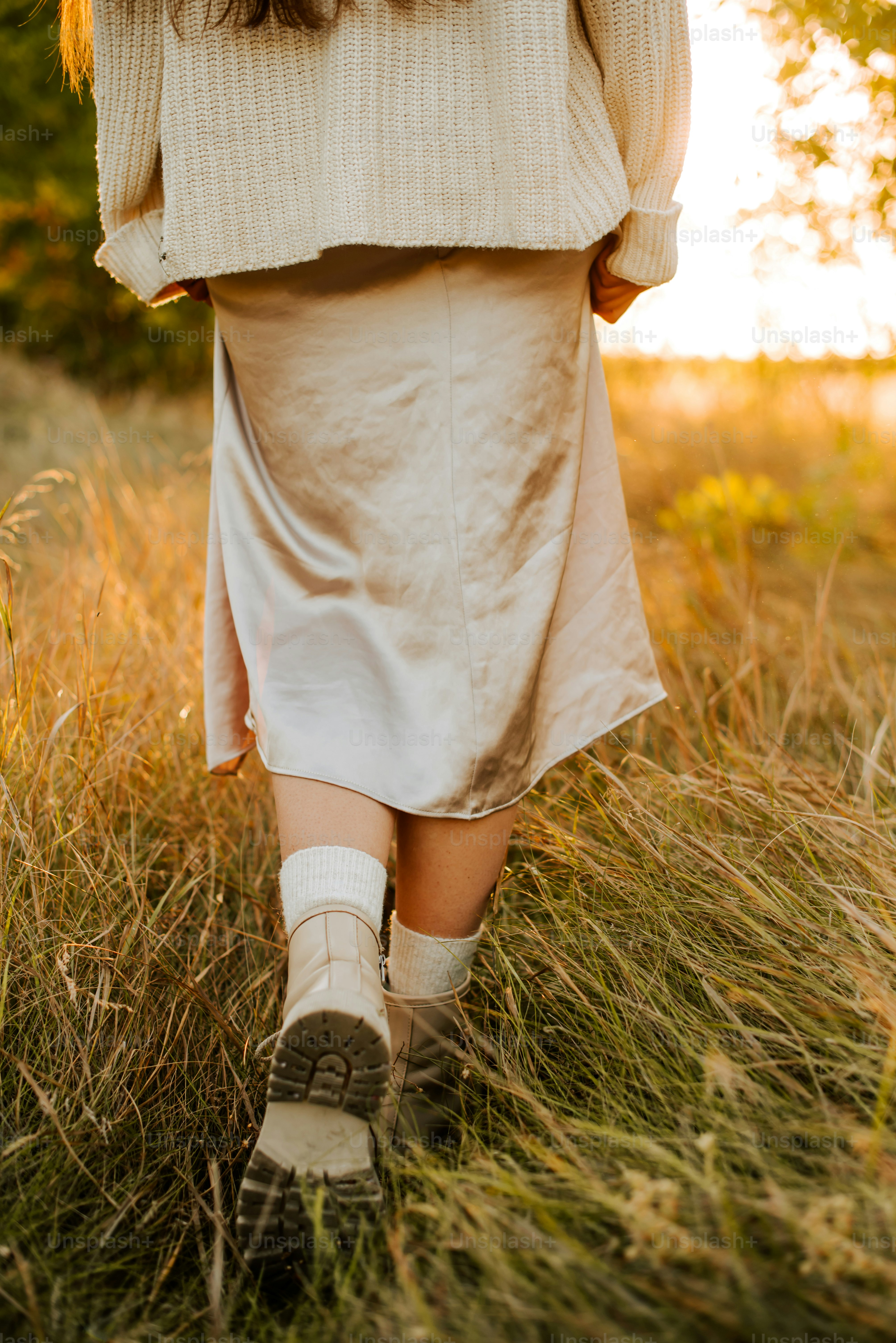 a woman walking through a grass covered field