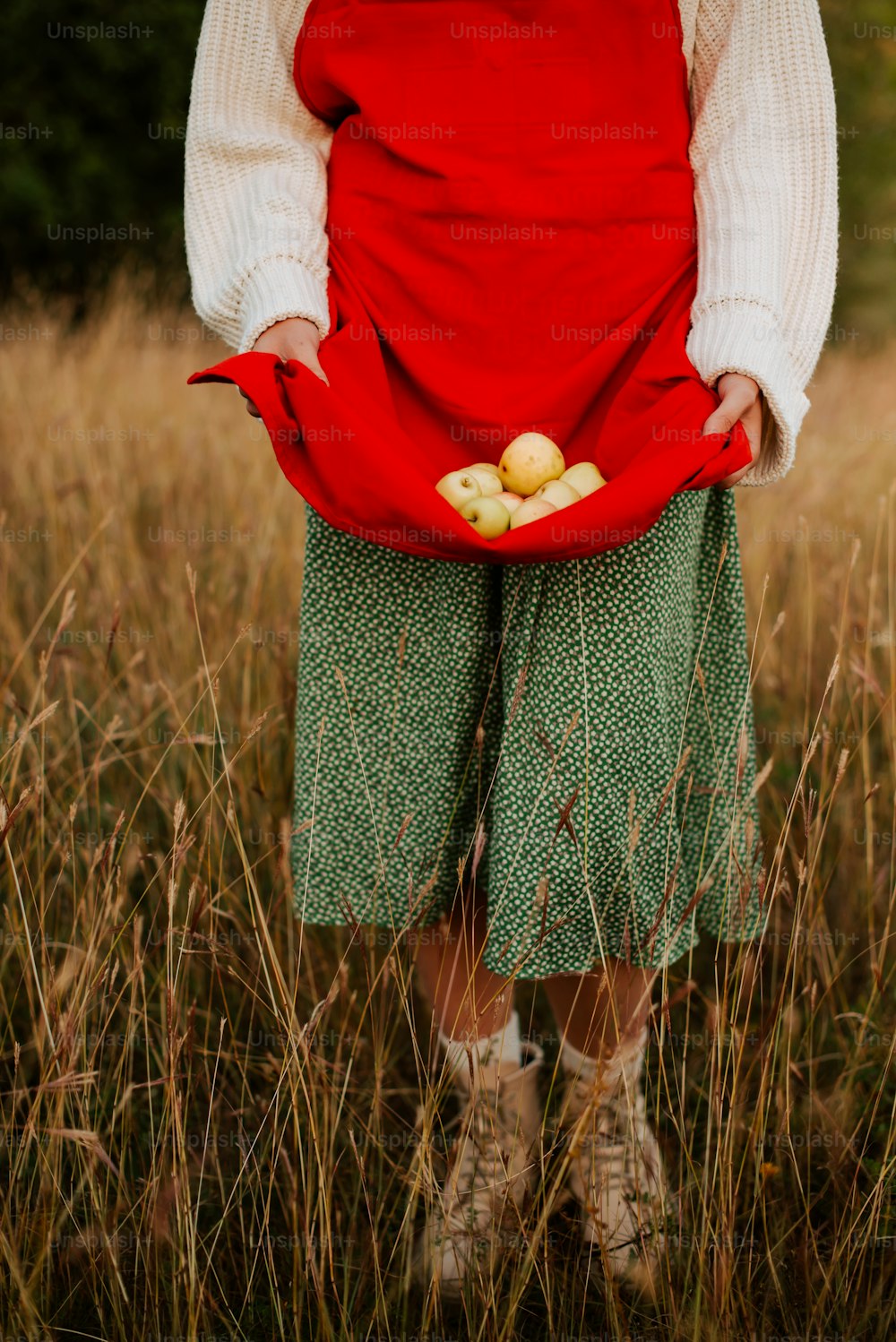 a person standing in a field holding a bag of apples