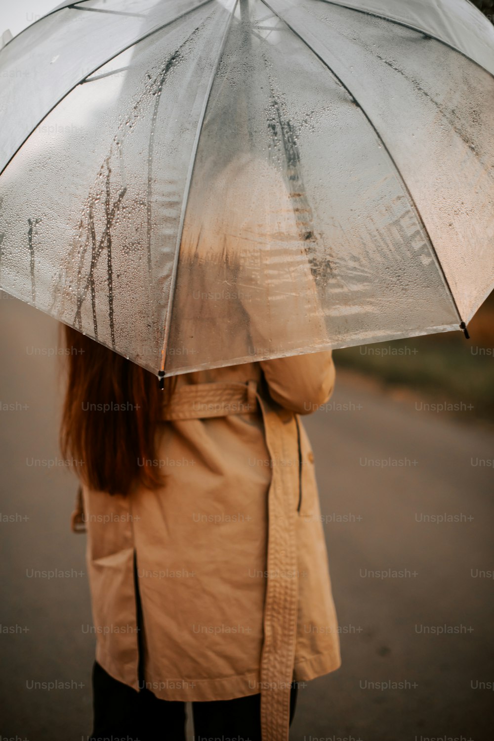 a woman holding an umbrella while standing on a road