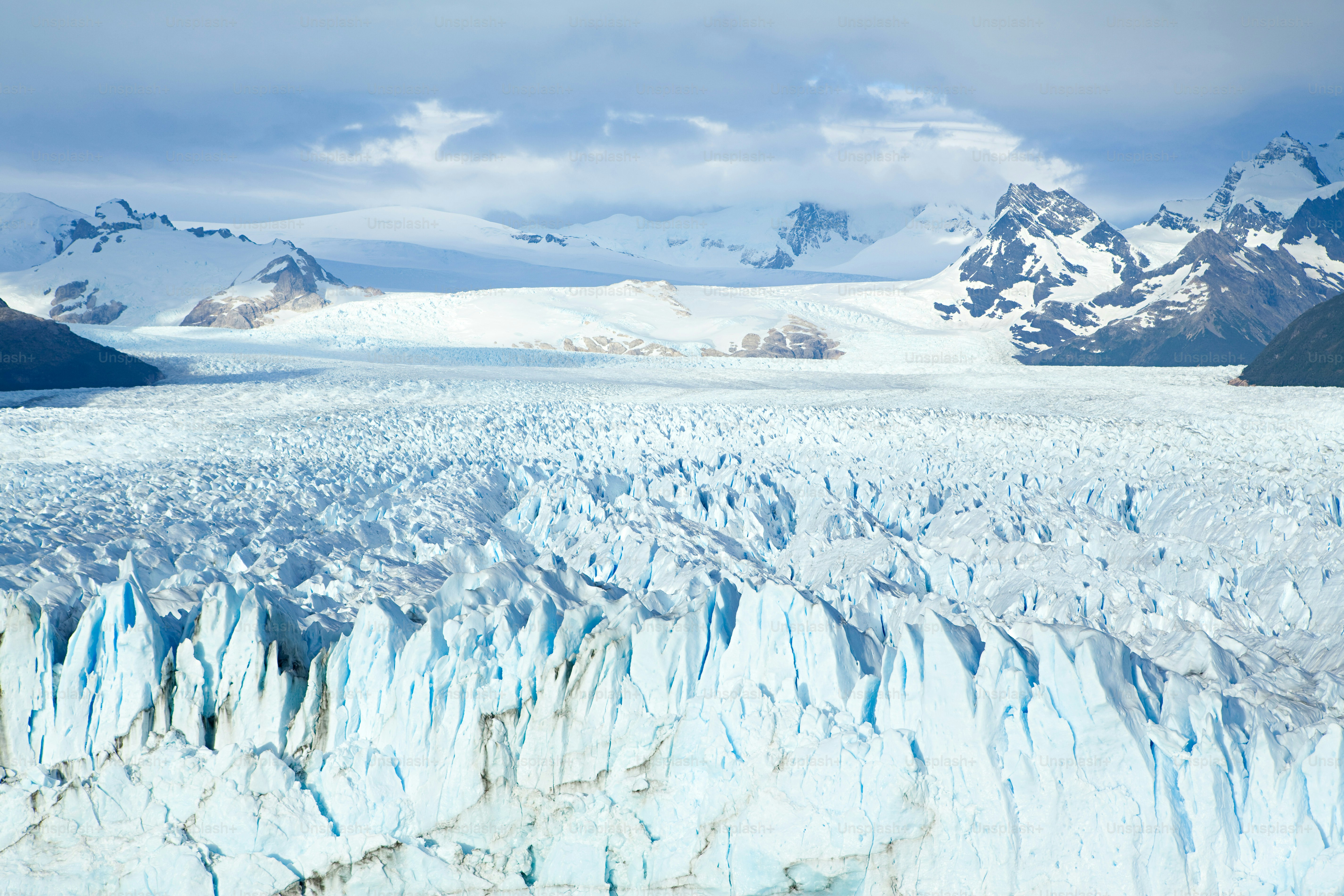a large glacier with mountains in the background