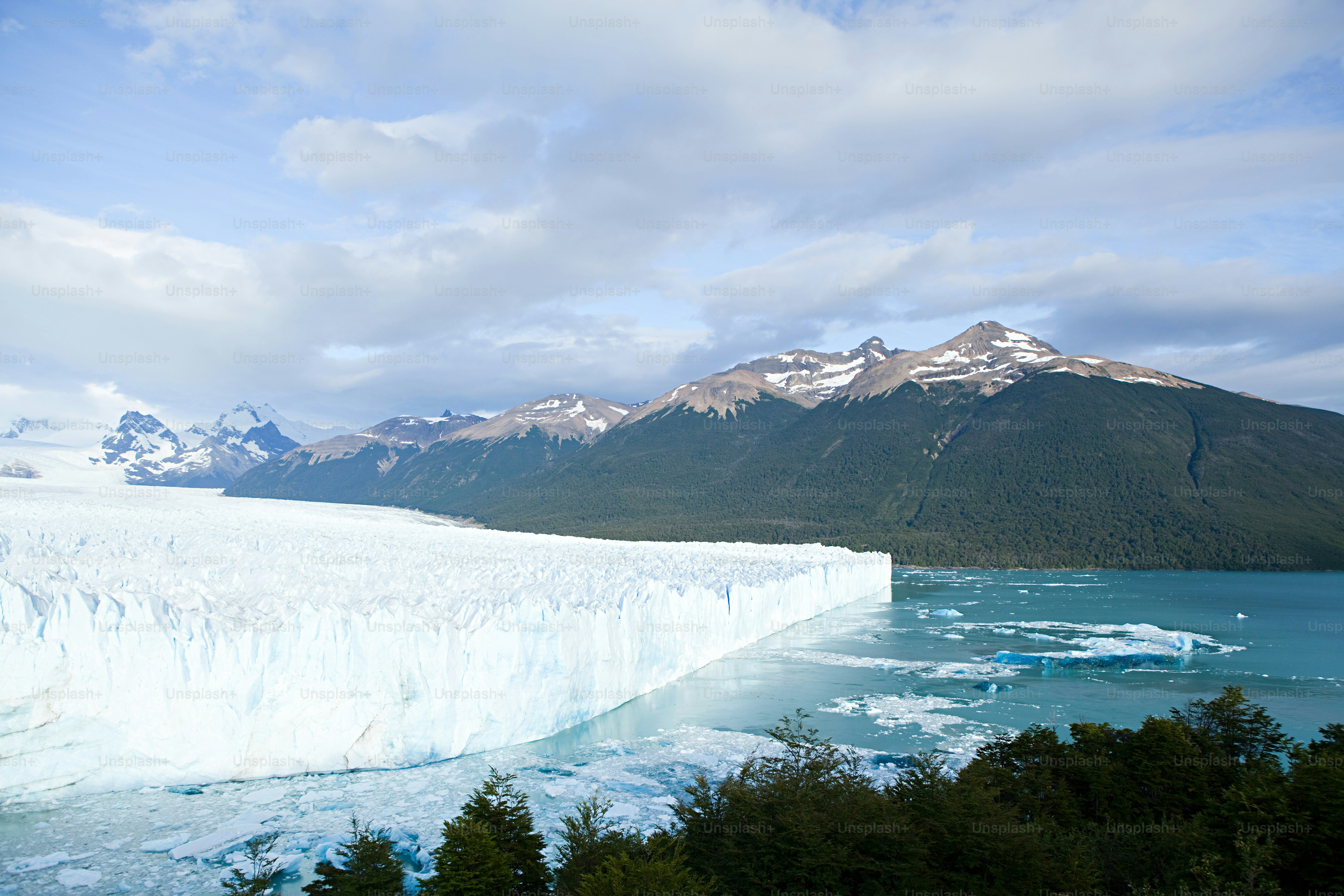 a large iceberg with mountains in the background