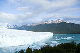 a large iceberg with mountains in the background