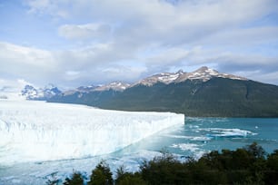 Un grand iceberg avec des montagnes en arrière-plan