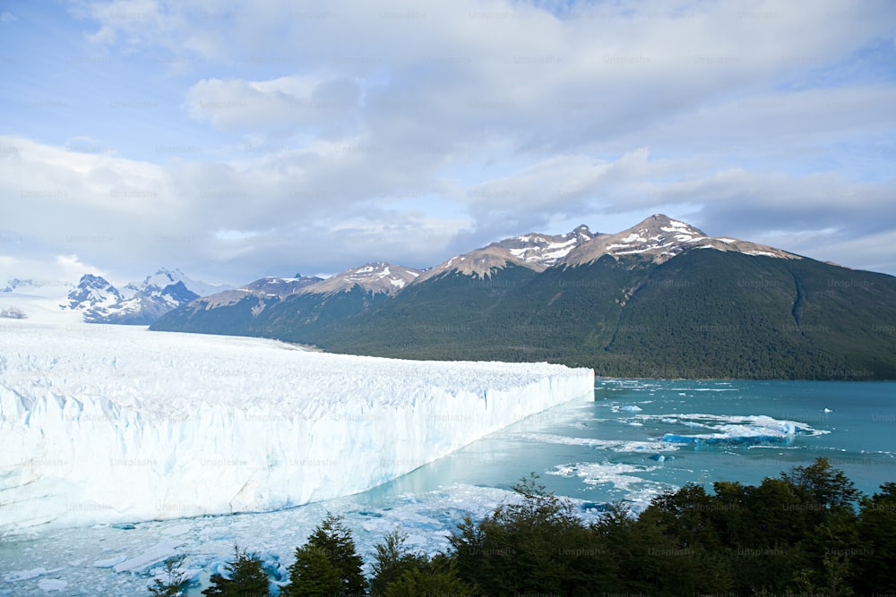 a large iceberg with mountains in the background