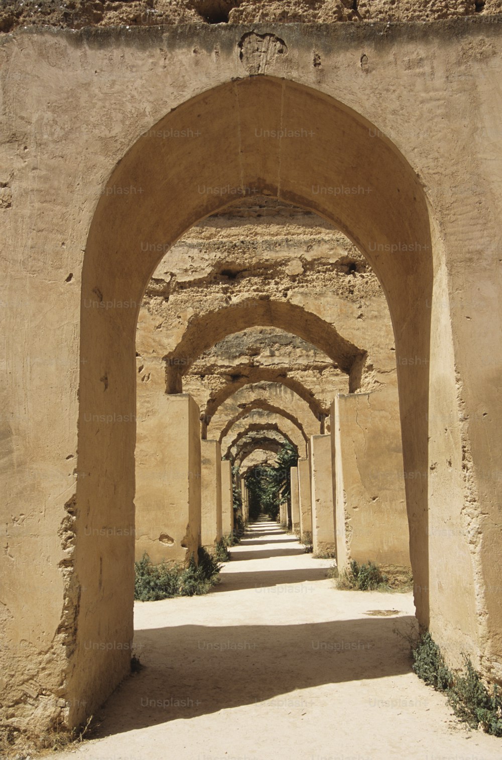 an archway in a stone building with a walkway between it