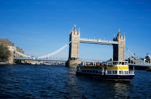 um barco amarelo e azul em frente a uma ponte