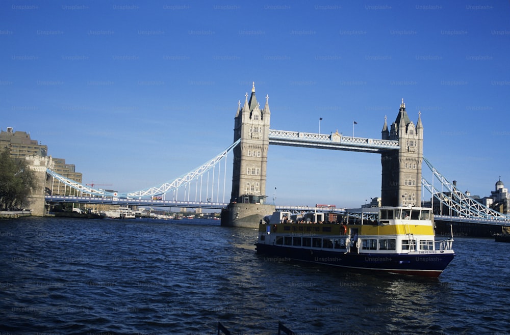 a yellow and blue boat in front of a bridge