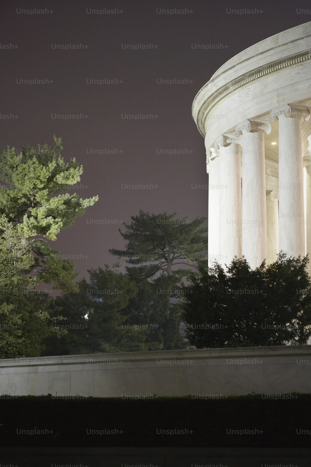 a white building with columns and trees in the background