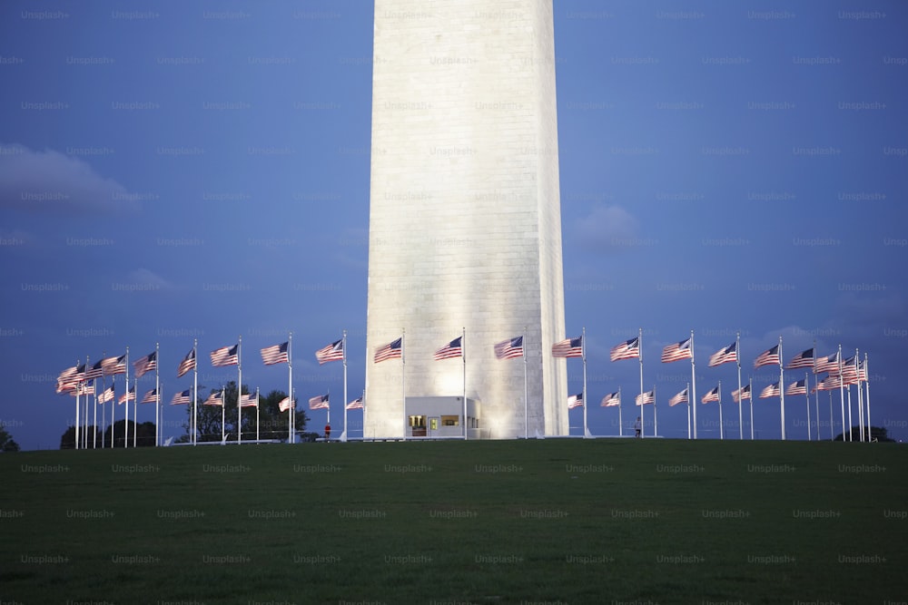 ワシントン記念塔の前で飛んでいるアメリカ国旗のグループ