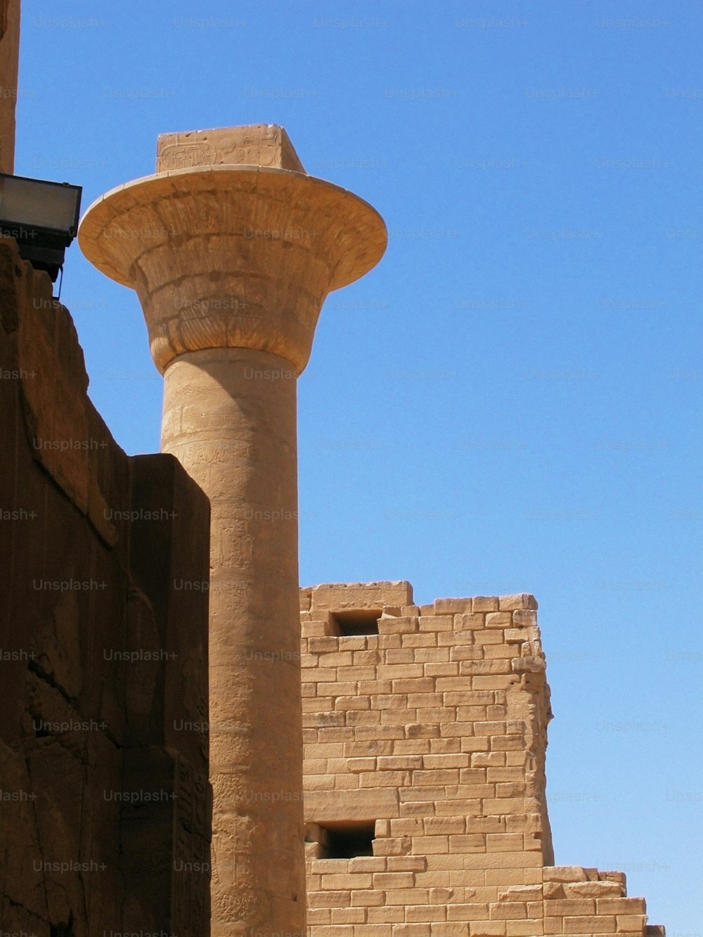 um alto pilar de pedra ao lado de um edifício de tijolos
