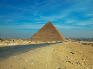 ein mann, der mit dem fahrrad eine straße neben einer großen pyramide hinunterfährt