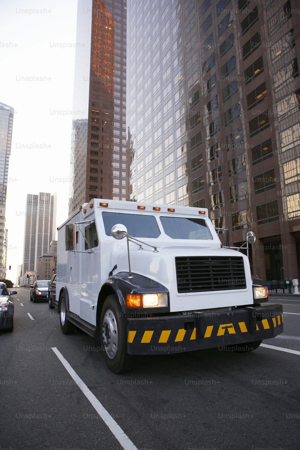 a white truck driving down a street next to tall buildings