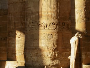 una estatua frente a unas columnas con escritura en ellas