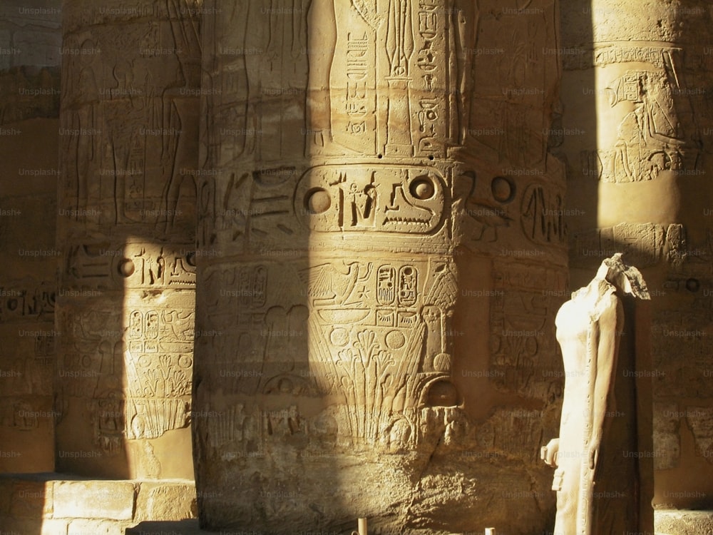 a statue in front of some columns with writing on them