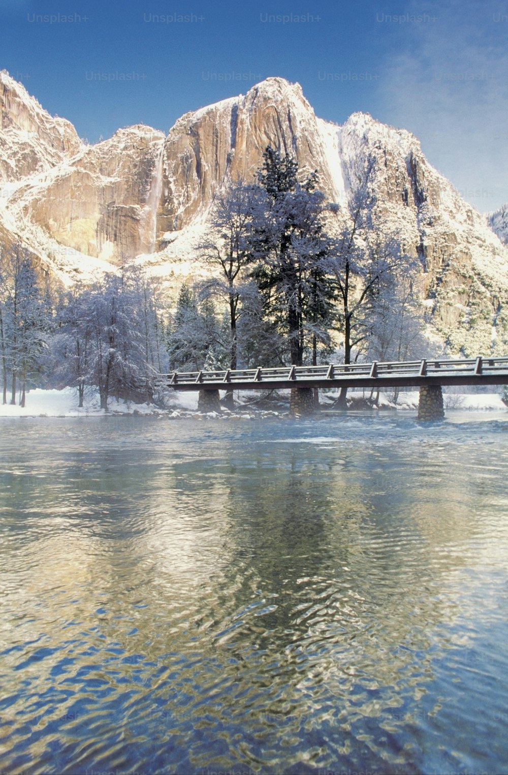 uma ponte sobre um corpo de água em frente a uma montanha