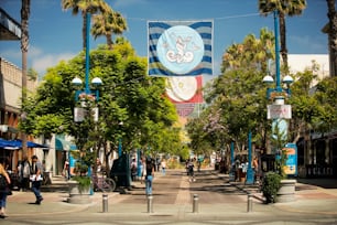 a street with palm trees and people walking on it